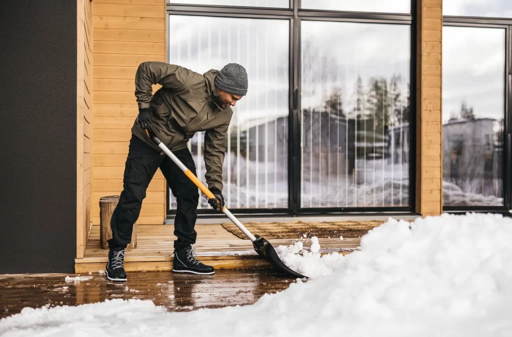 En man som skottar snö med en snöraka